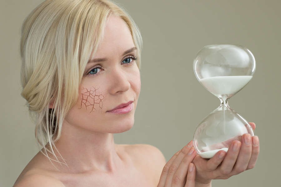 Beauty portrait of young woman holding hour glass sand timer, ag