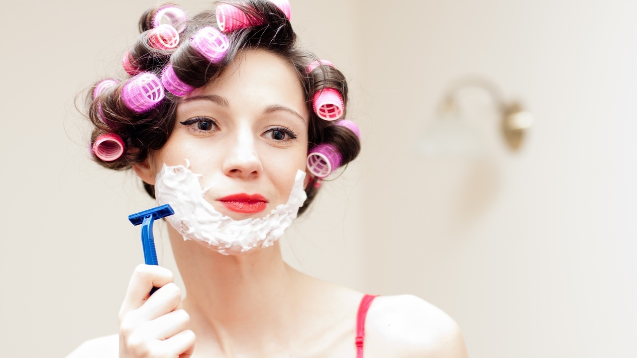 Beautiful funny girl shaving with foam &amp; razor her face