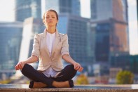 Business woman meditating outdoor over building background